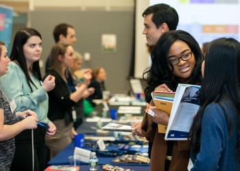 Students converse at career fair held at the Arlington George Mason University Campus, home to many graduate programs.