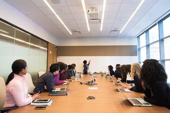 People gathered around a conference table looking at the presenter in the front of the room. 