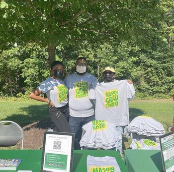Graduate Student Life team members at SciTech Welcome Fair. They are wearing the 2022 Mason Grad Student t-shirts and handing out other giveaways.